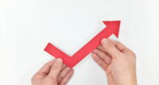 Hand holding red arrow upward. Economy and business recovery and
